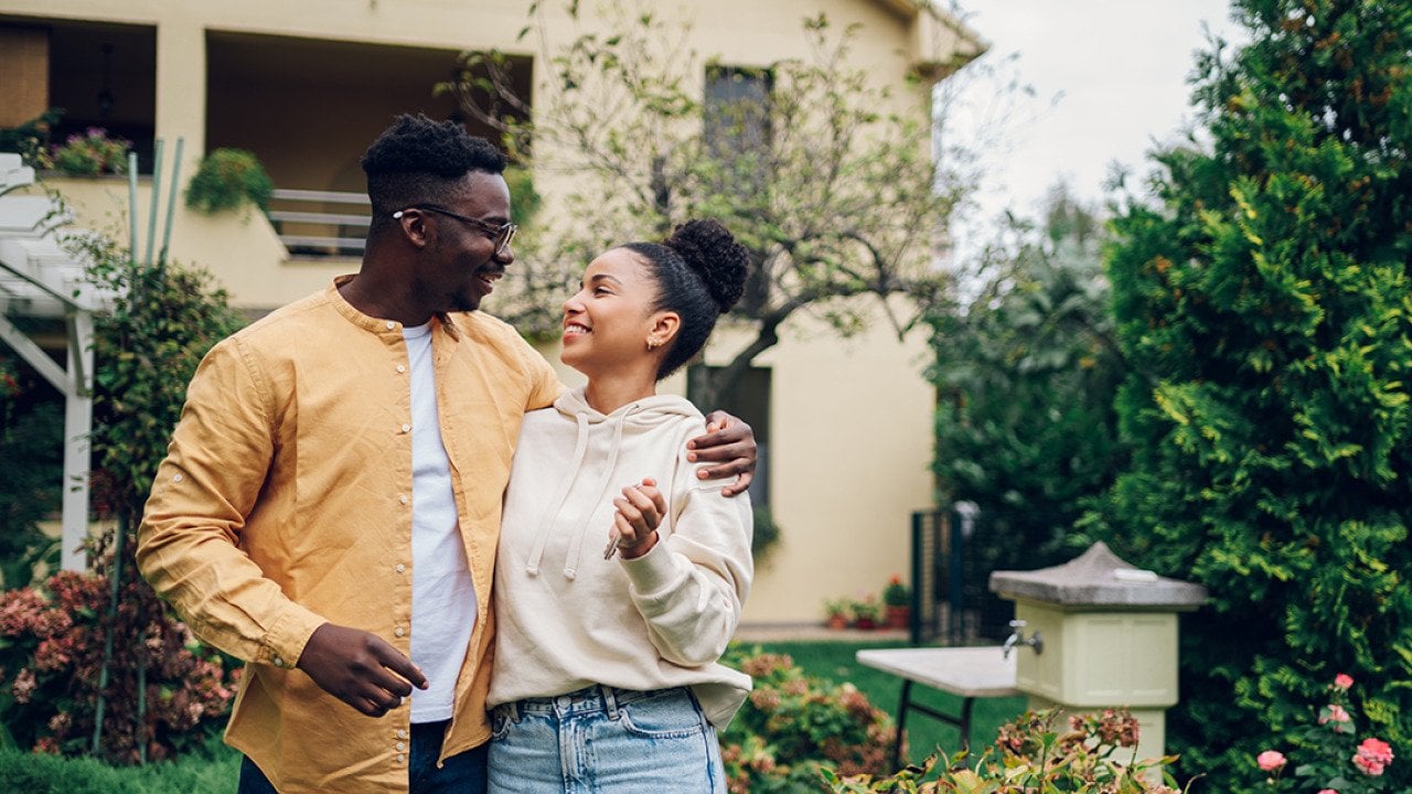 A couple standing outside their new home after moving in. 