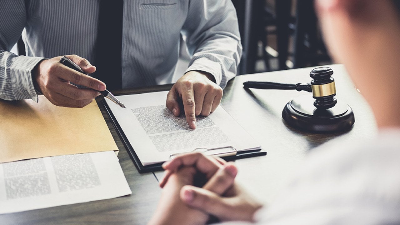 A lawyer consulting with his client and reviewing documents.