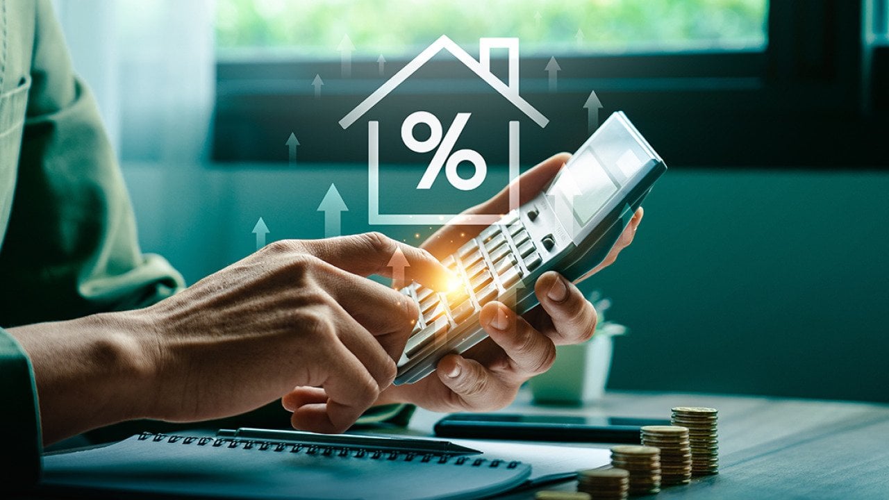 Person using a calculator illustrated with increasing mortgage rate concep graphics.