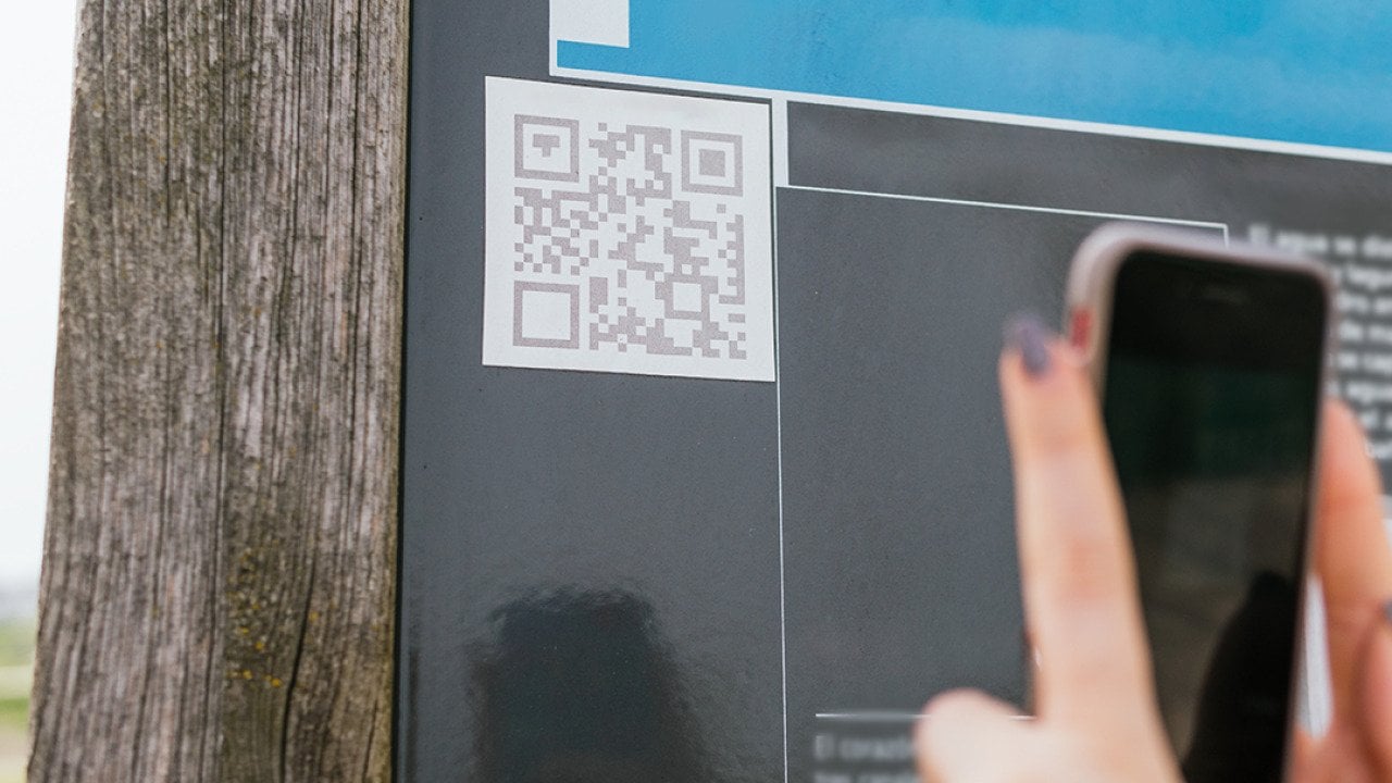 User scanning a QR code on a wall with a phone.