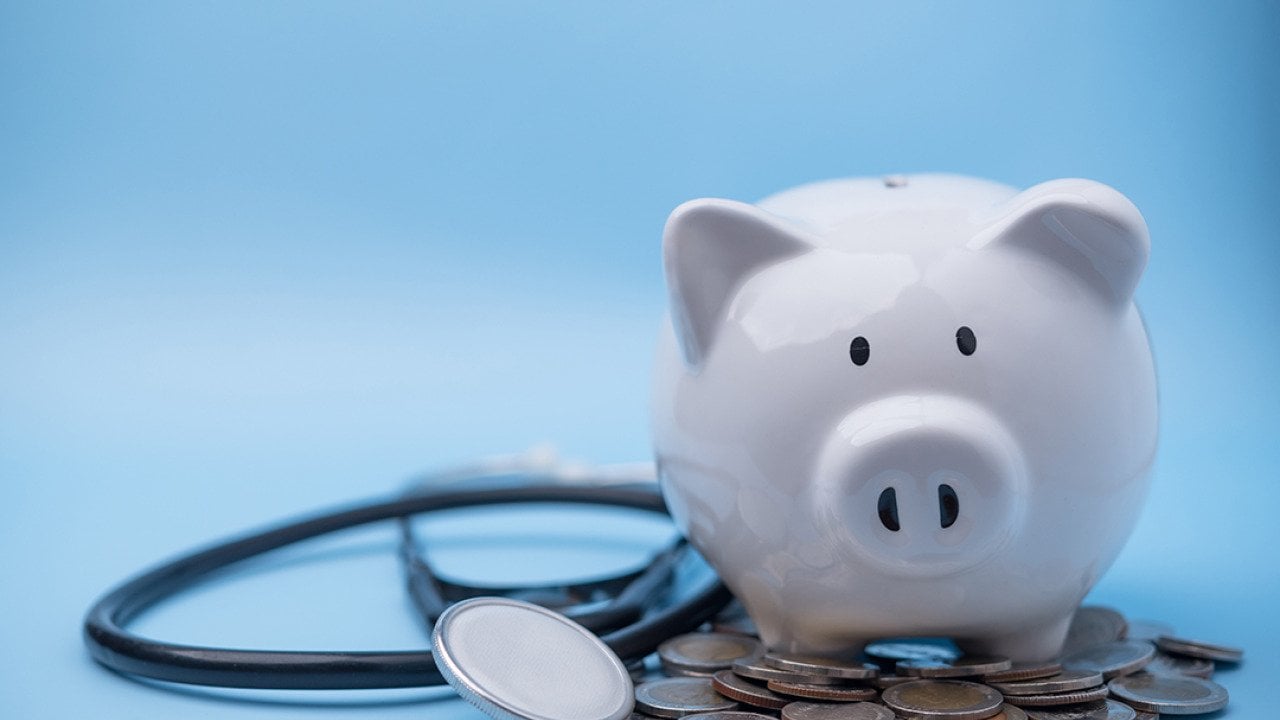 A piggy bank with coins and a stethoscope.