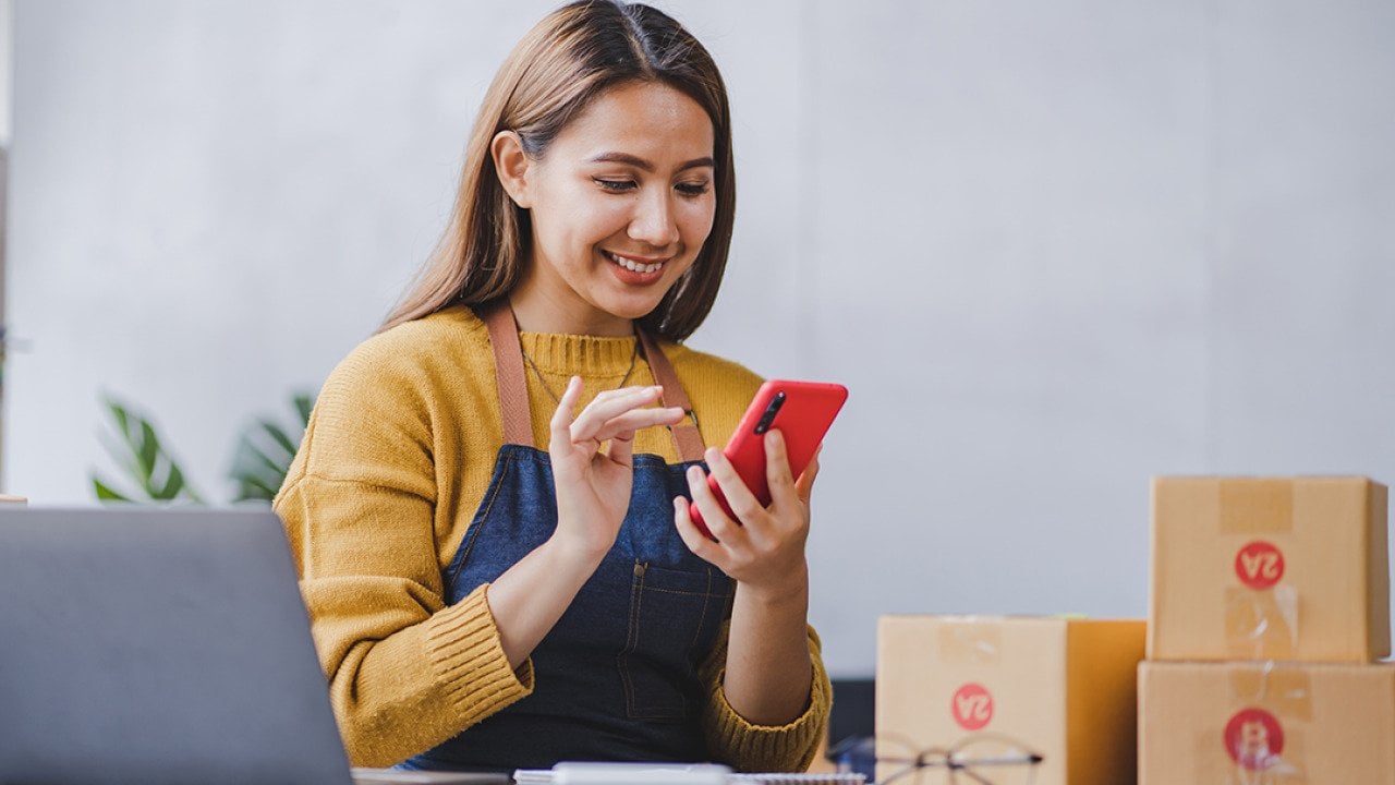 An entrepreneur checking and packing orders from her online marketplace.