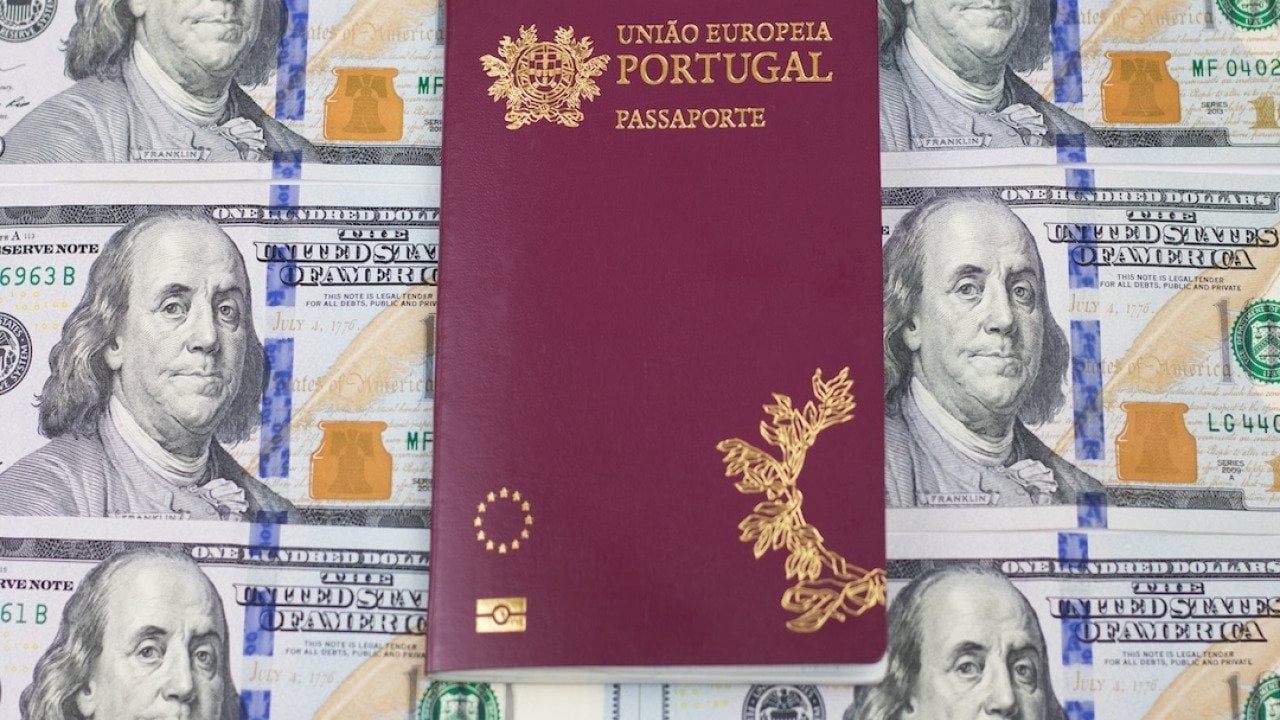 A Portuguese passport on top of one hundred U.S. dollar bills.