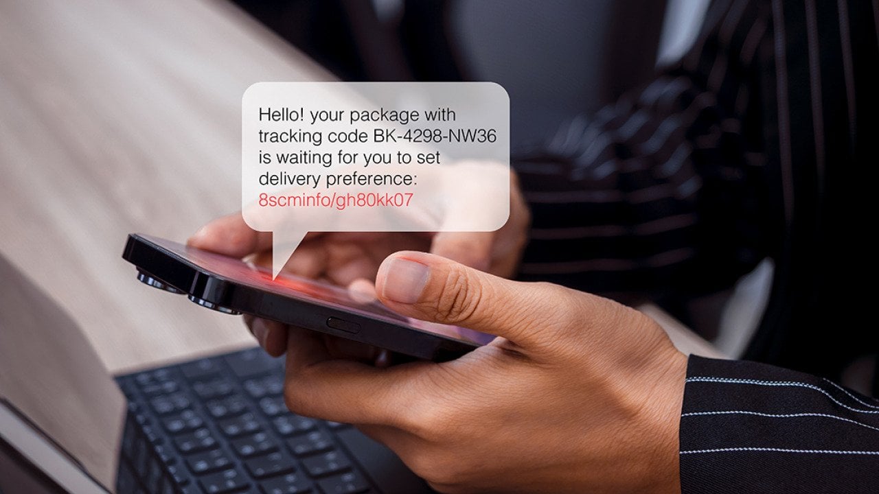 Person using phone with an illustration of an SMS bubble showing potential scam with phishing link.