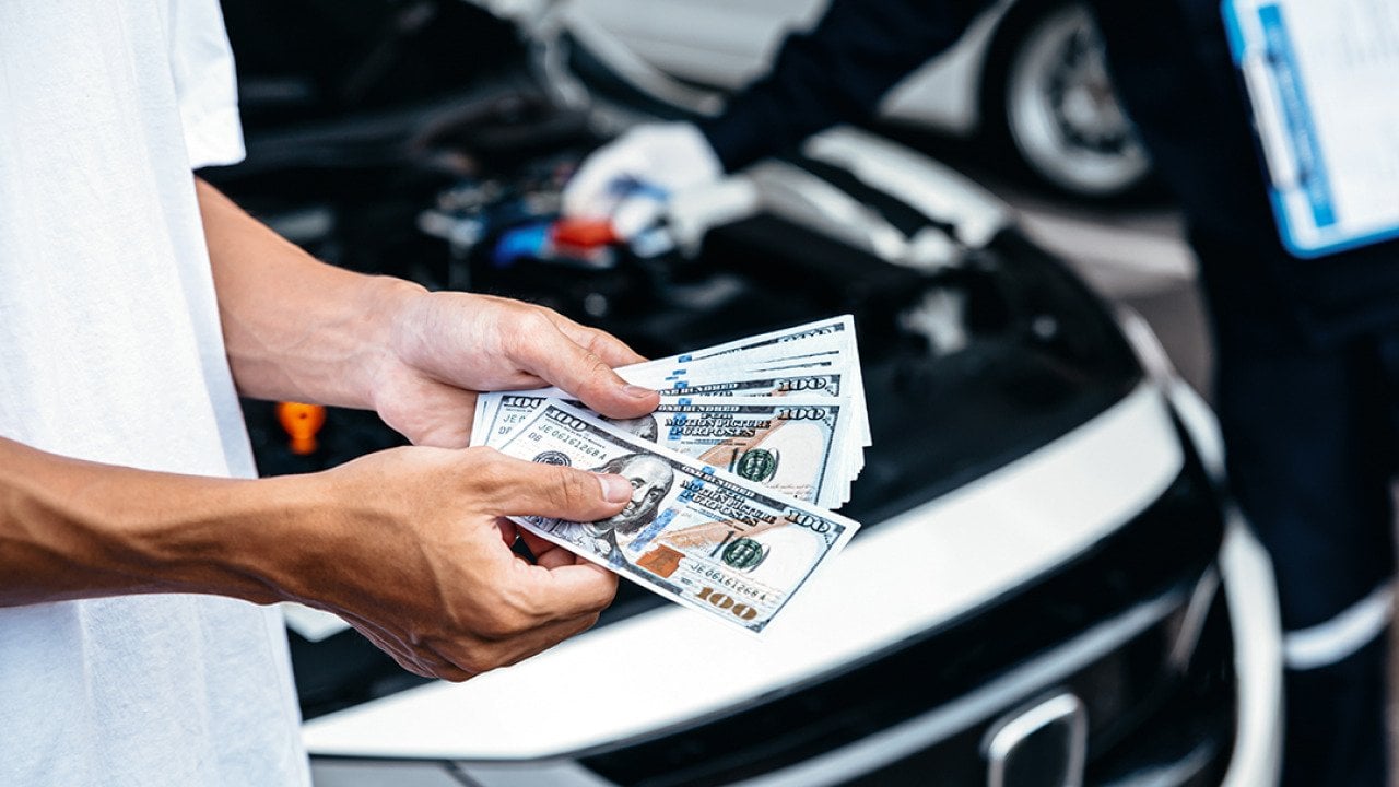 Customer pays with cash to the car mechanic after a service.