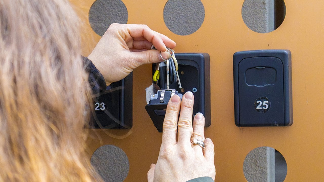 A person putting keys inside an apartment key box.