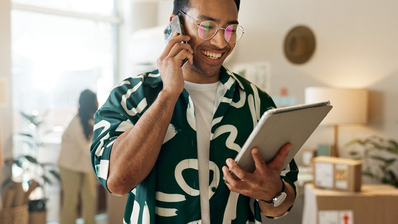A man on the phone and looking at a tablet for an order.