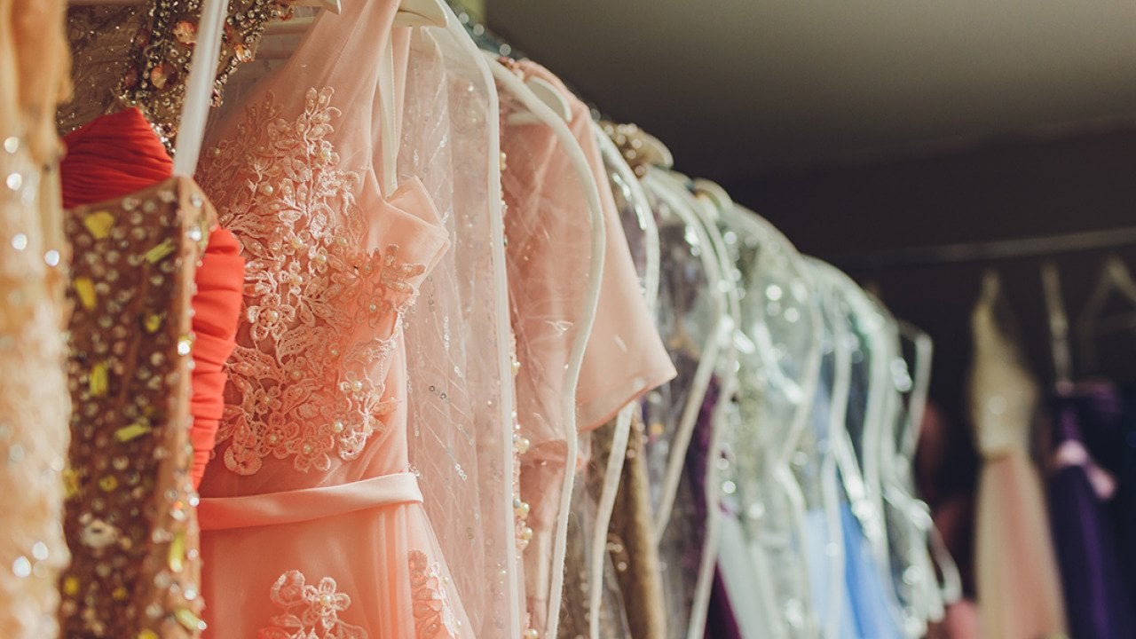 A row of ladies' long gown dresses in a closet.