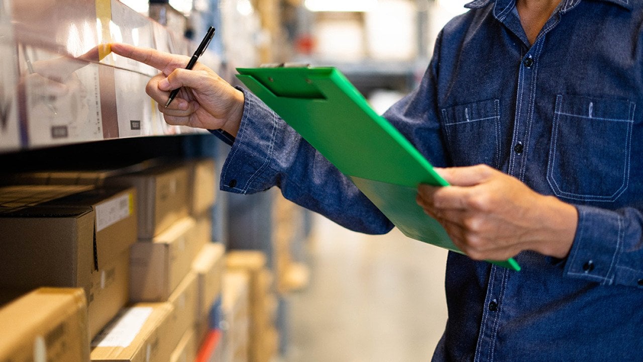 A factory assistant checking stocks for an inventory at a warehouse.