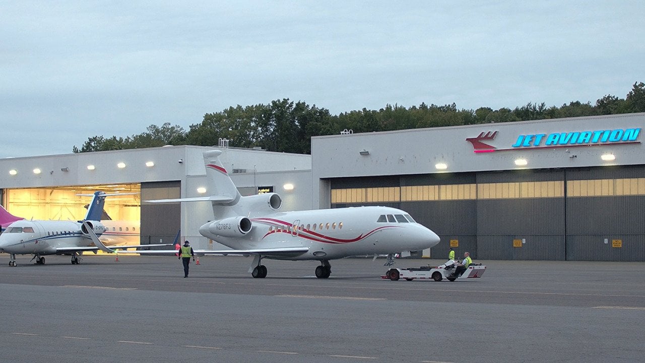 Line technicians working at the Teterboro Airport, operating aircraft towing vehicles and parking airplanes in the hangar.