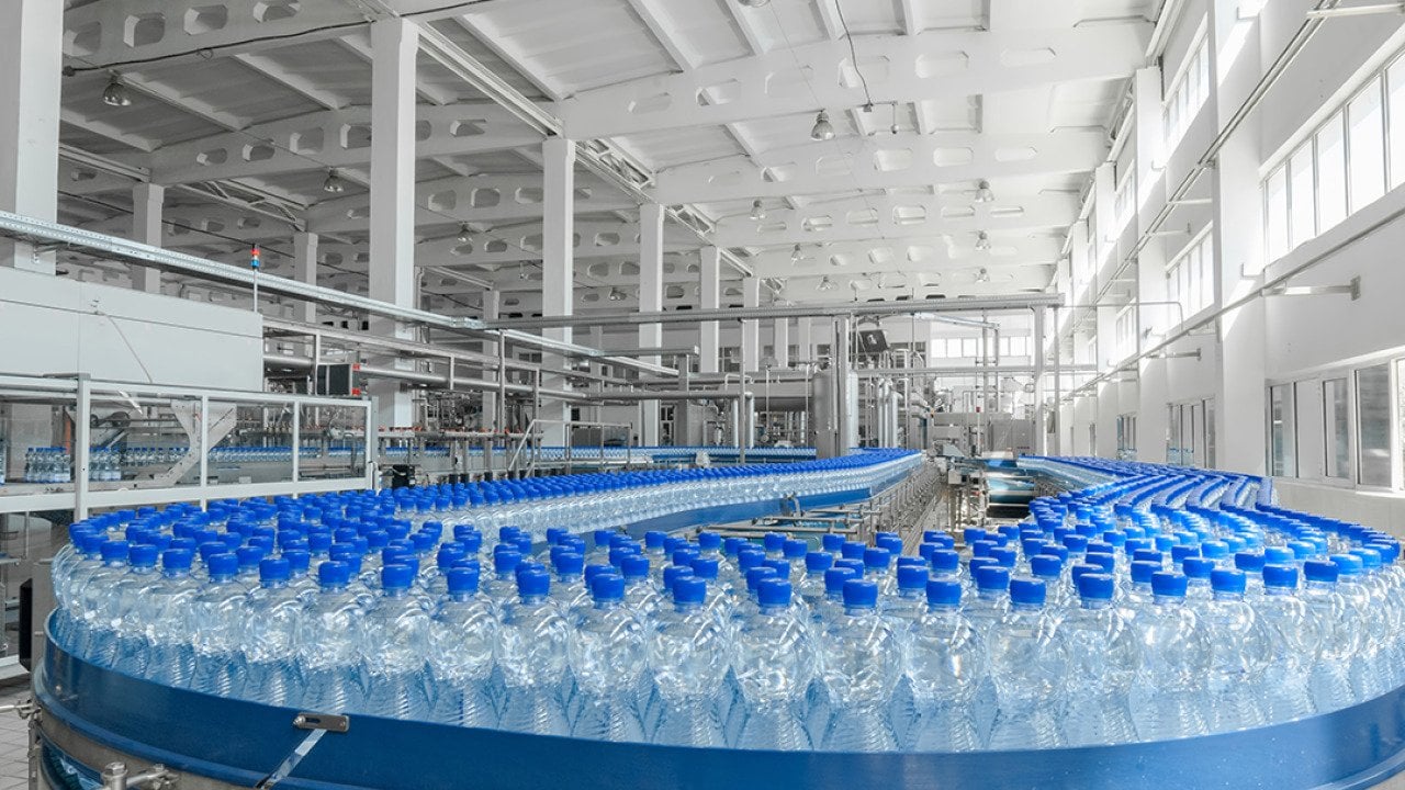 Massive production of plastic bottles on factory's conveyor belt.