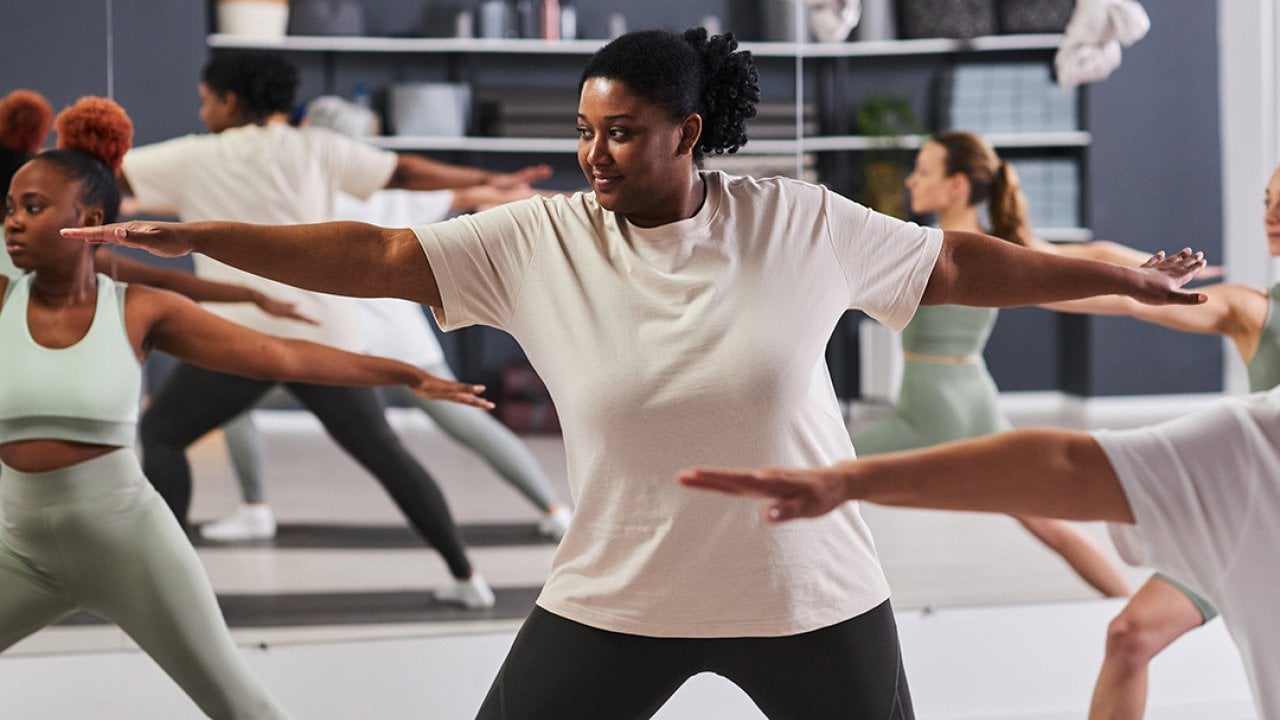 Focus on a black woman among a group doing aerobics together in a studio.