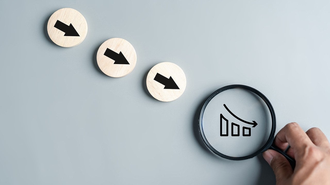 Downward arrows and a magnifier focused on a declining chart as a concept of inflation.