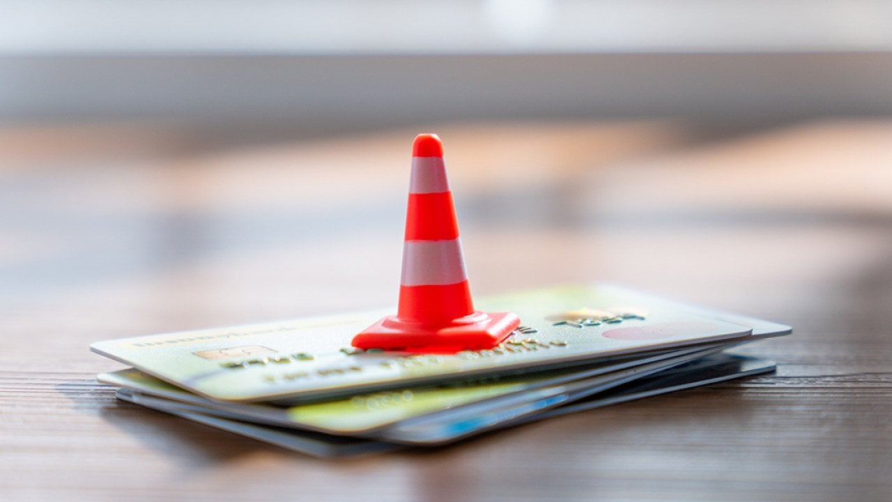 A traffic cone on a stack of credit cards. 