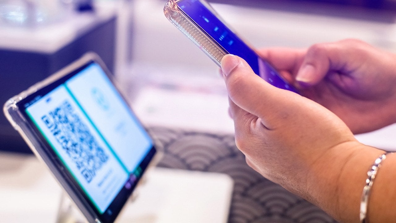 A person using a smart phone to scan a QR code from a smart device for a digital registration.