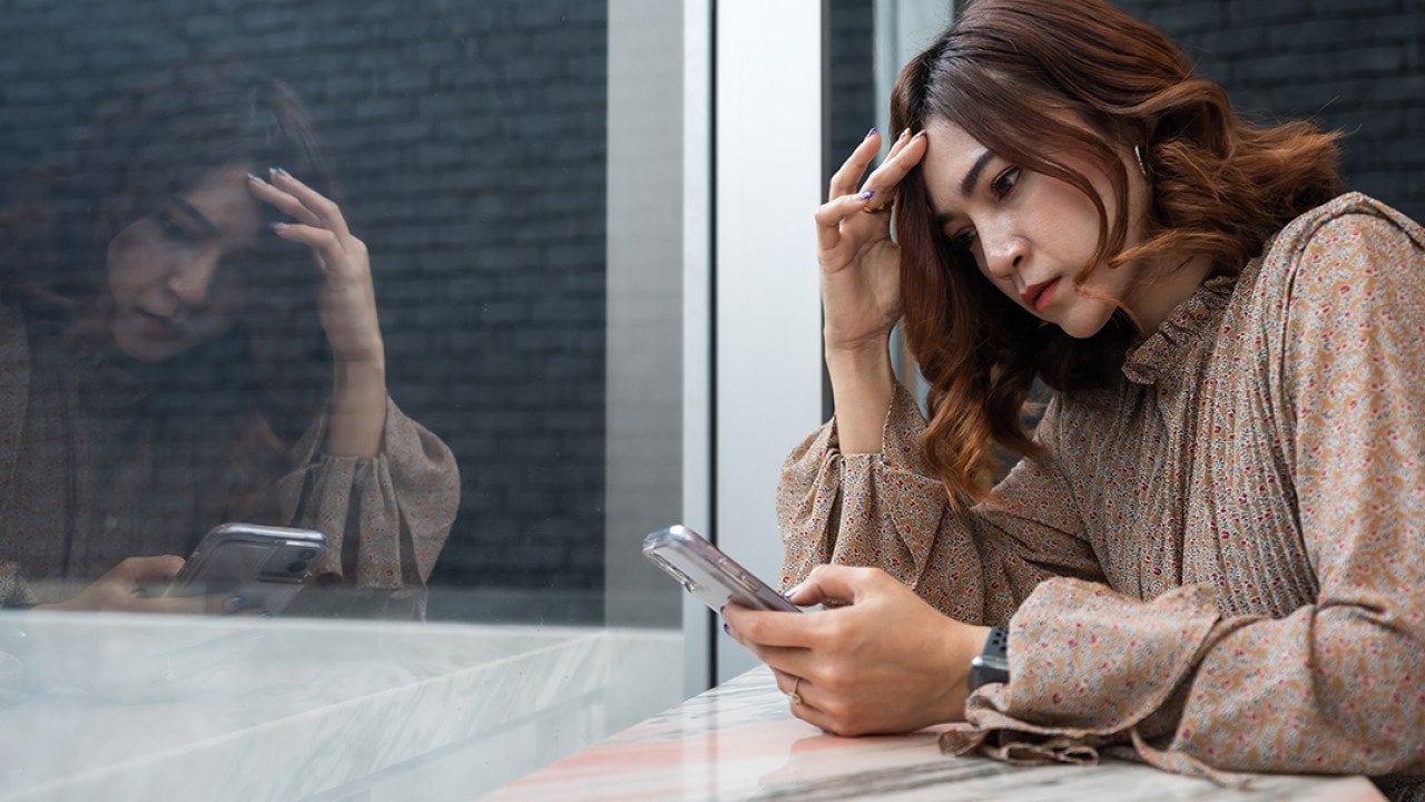 A person checking on her phone, while looking worried about something.