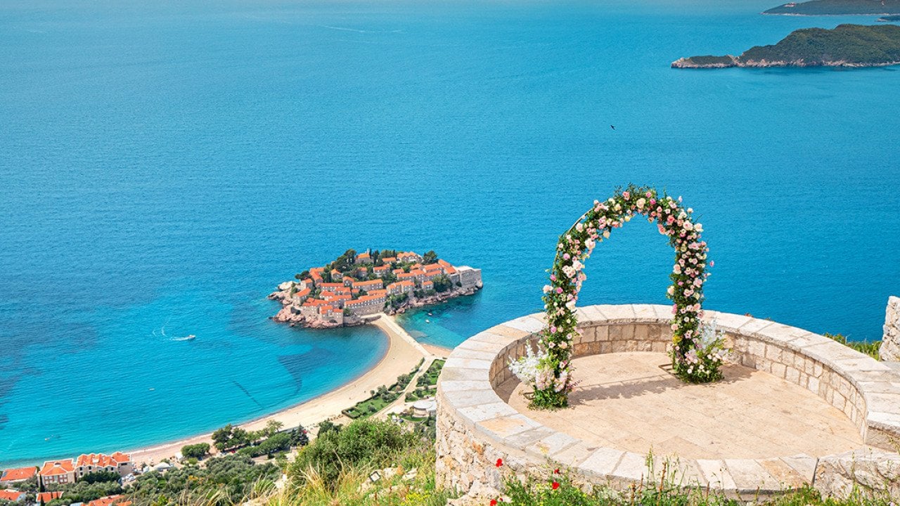 A romantic wedding ceremony at Montenegro Sveti Stefan viewpoint, with an arch adorned in flowers overlooking the Adriatic Sea.