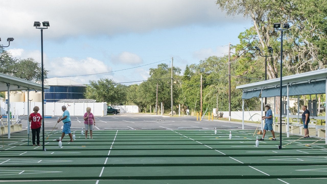 Older people playing shuffleboard at a resort.