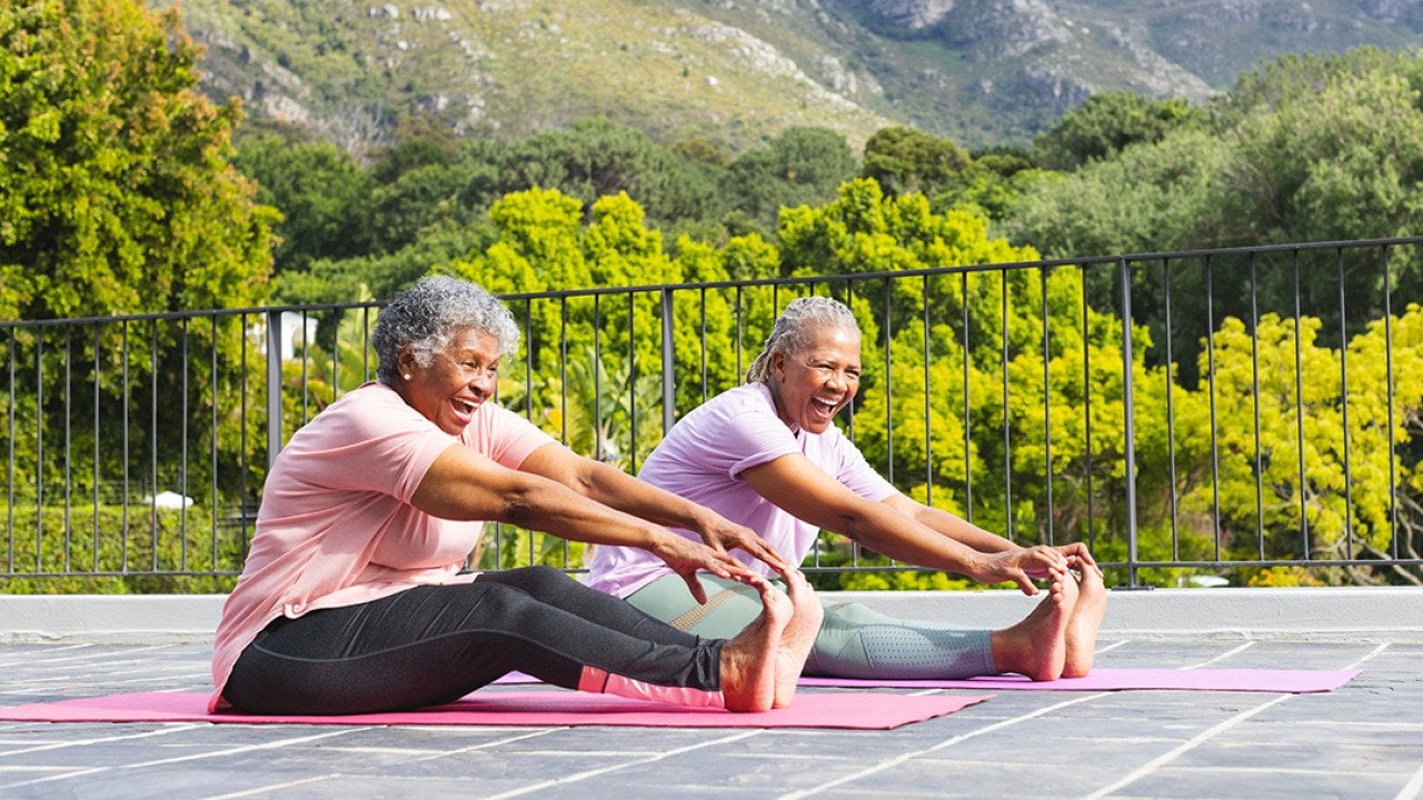 Two elderly women stretching their bodies during an outdoor yoga.