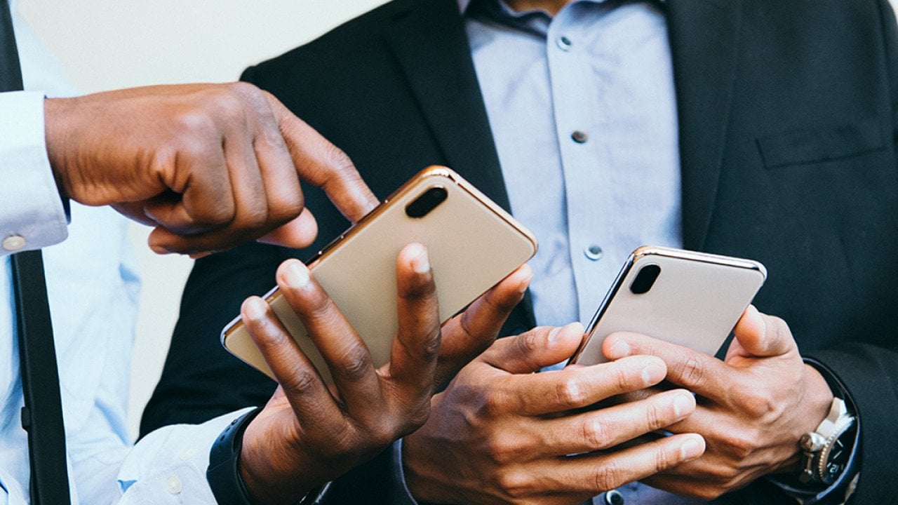 A business person showing an online post from his smartphone to a colleague. 