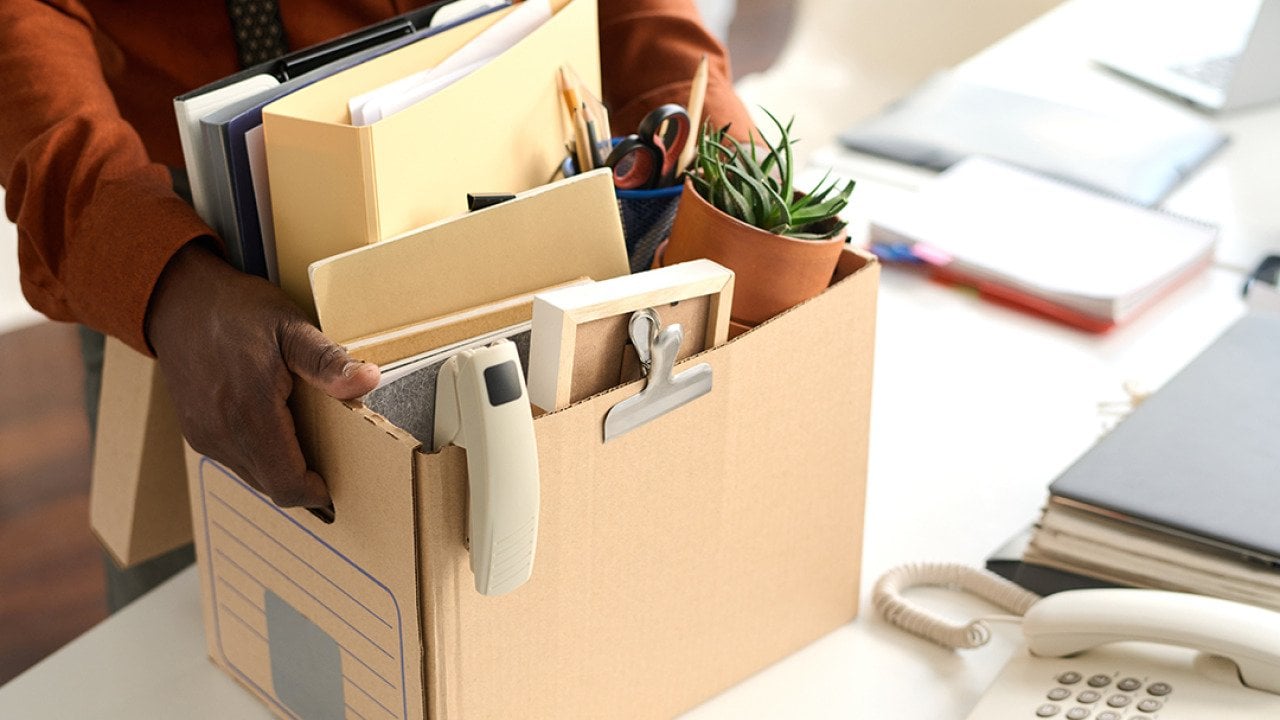 An office worker packing personal office items to a box. 