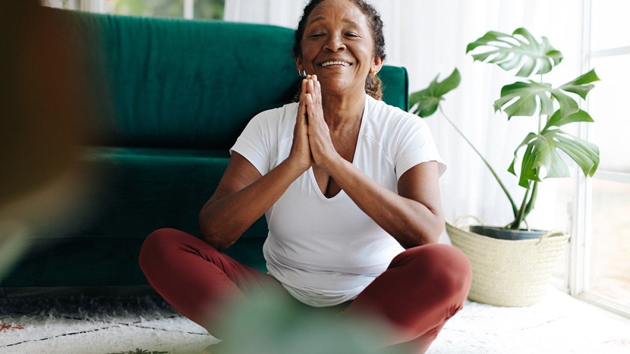 A elderly person practicing meditation in a prayer pose during a yoga session.