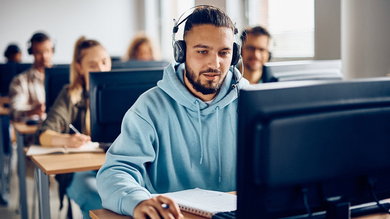 A male university student using a desktop computer during a class.