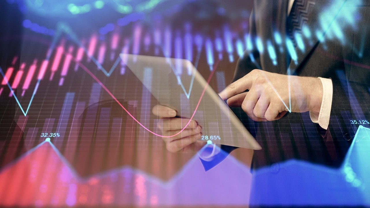 A financial marketer using a tablet with an overlay of forex graphs.