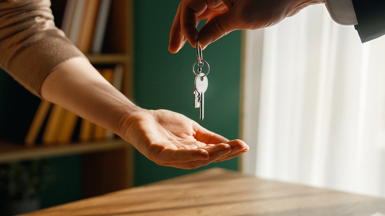 A new homeowner receives keys from real estate agent.