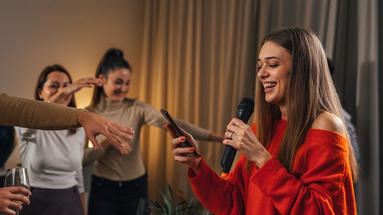 A young woman sings karaoke at a house party.