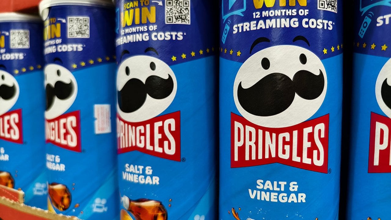 Cans of Pringles on a shelf featuring a QR code for a contest.
