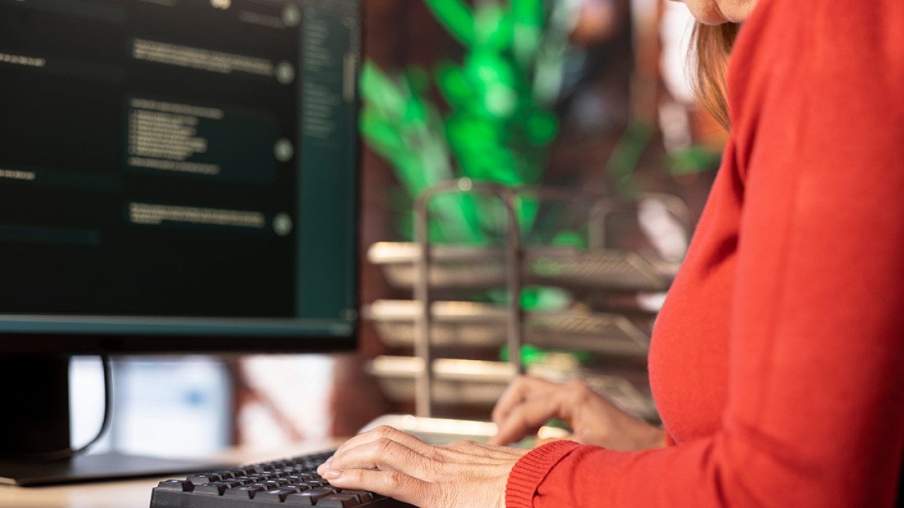 A female employee typing on a keyboard while working in an office.