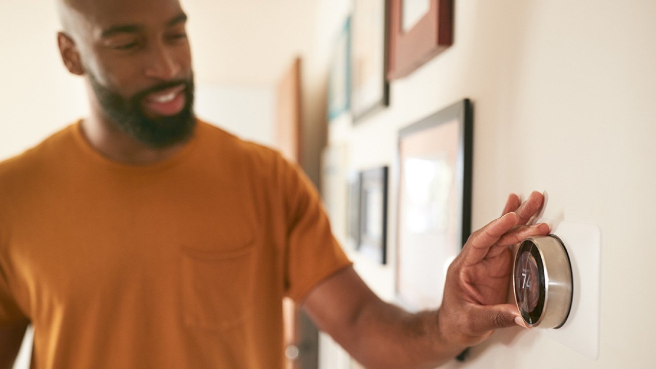 A man adjusting the thermostat at home.