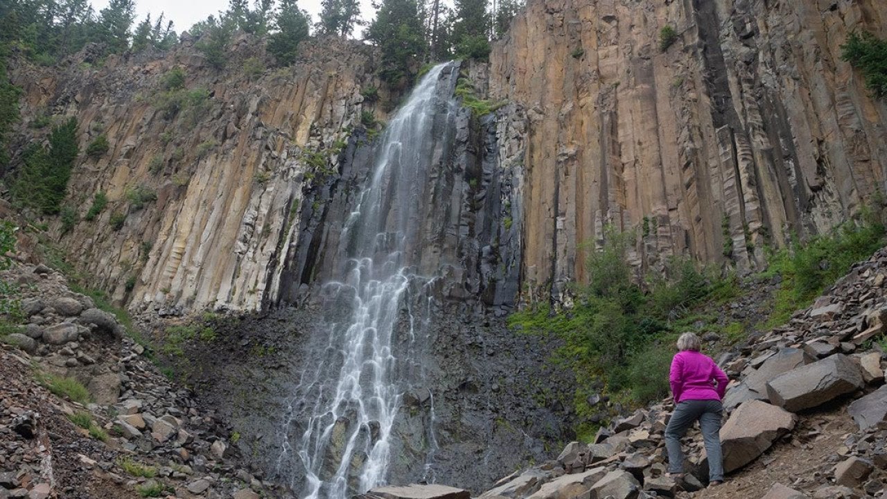 A senior woman at the base of Palisade Falls in Montana.