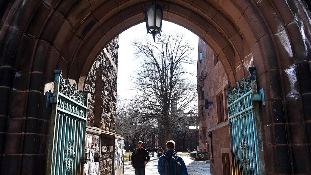 Students passing through an entrance to Yale University's old campus in New Haven, Connecticut, USA.