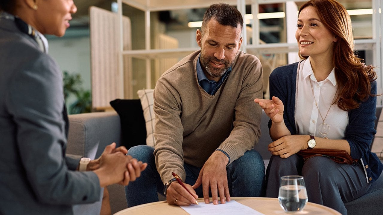 A couple meeting with a financial advisor for an insurance's contract signing.