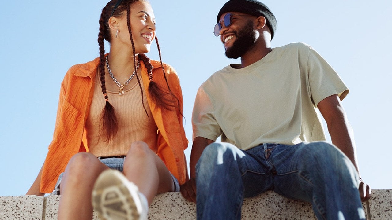 A couple bonding together while enjoying in a sitting wall outdoors.