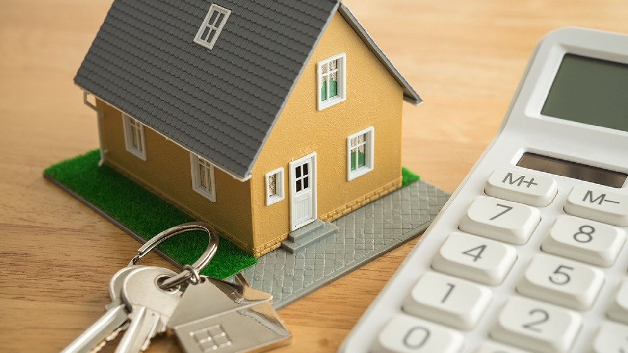 A small house model, house keys, and a white calculator as a concept of calculating rent.