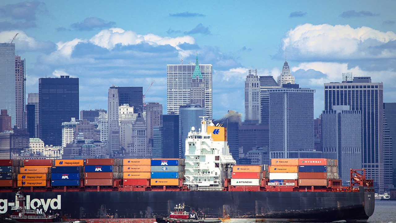 A large container ship carrying imported products entering a port in New York.