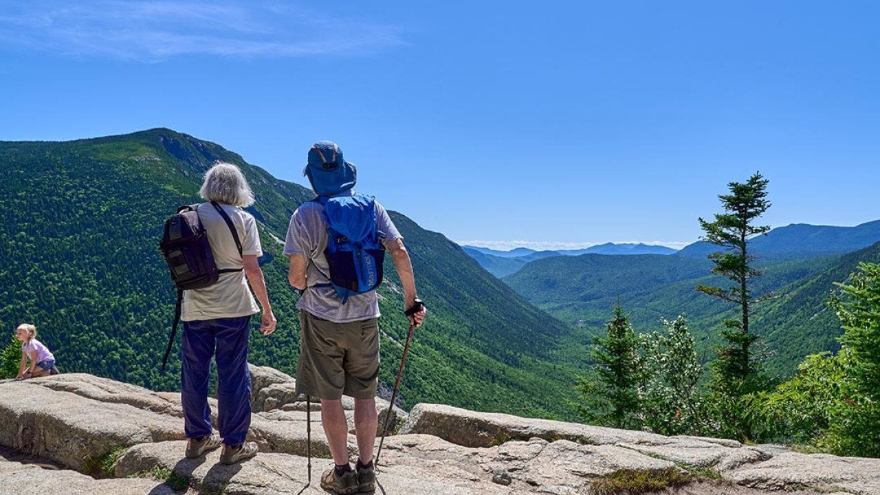 Hikers looking at the scenic view of the Crawford Notch from Mt. Willard in Carroll Country, New Hampshire, USA.