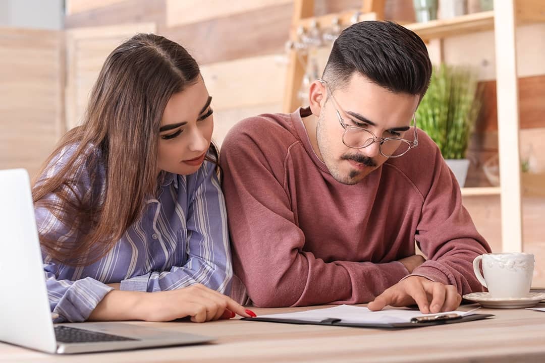A young couple reviewing an insurance contract in a cafe.