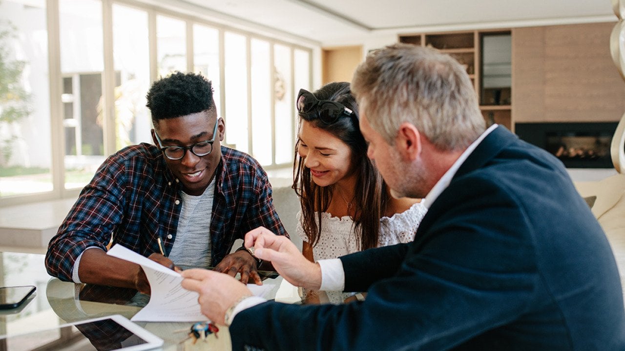 A young couple signing a property contract with a real estate professional.