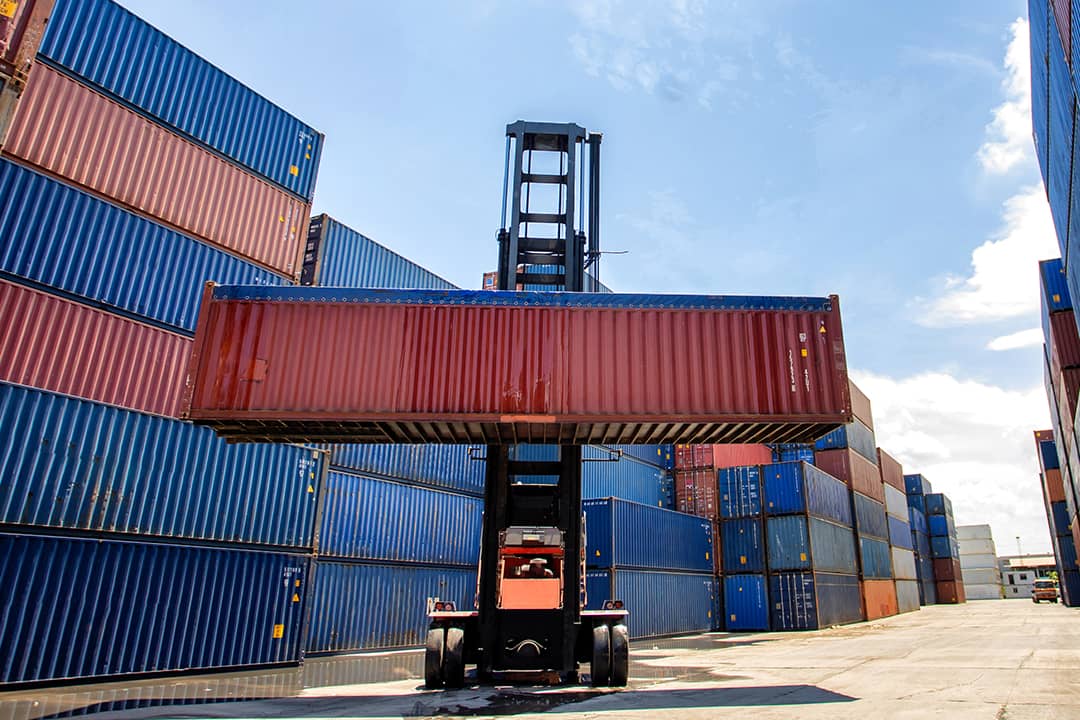 A cargo container being lifted in a shipping yard.