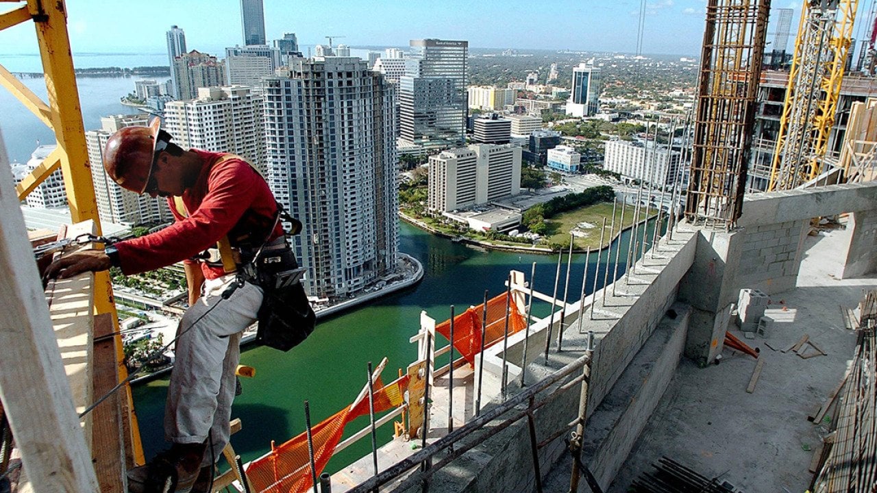 A construction worker makes his way up the side of a condominium highrise construction site in downtown Miami, Florida.