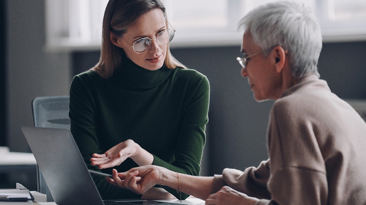 A financial advisor discussing plan options for a life insurance with an elderly client in the office.