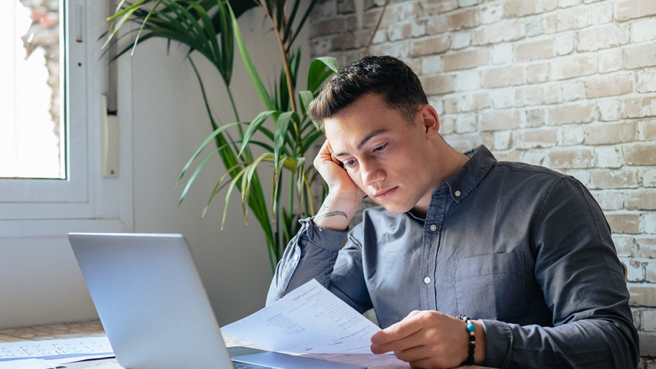 A young adult reviewing an official loan document for personal finance matters.
