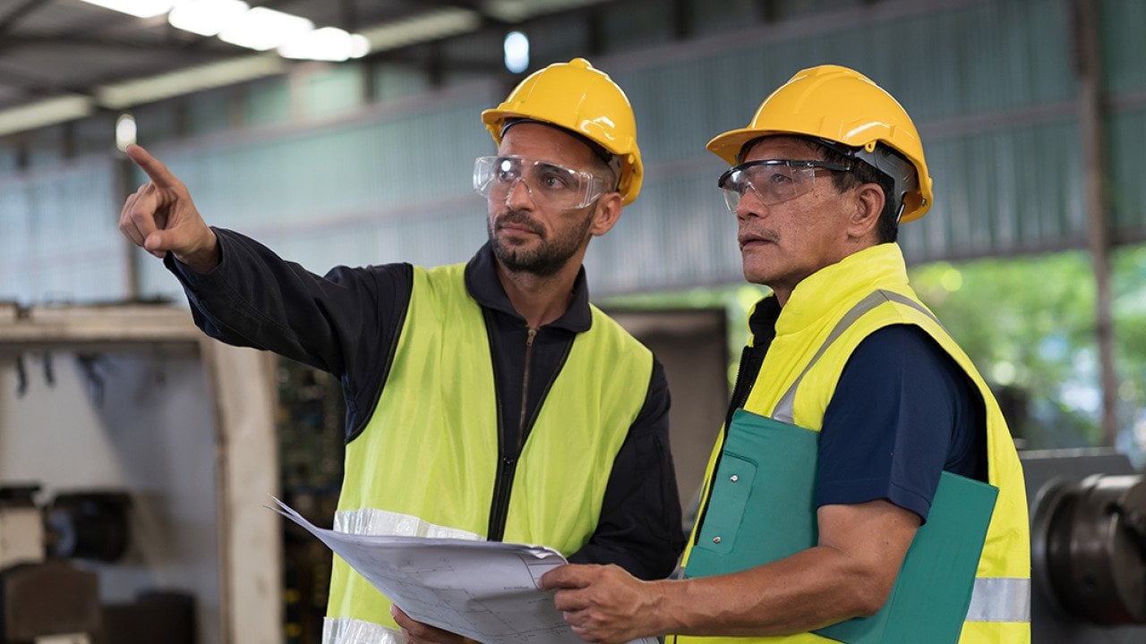 Engineers discussing on work maintenance issues in their industry factory.
