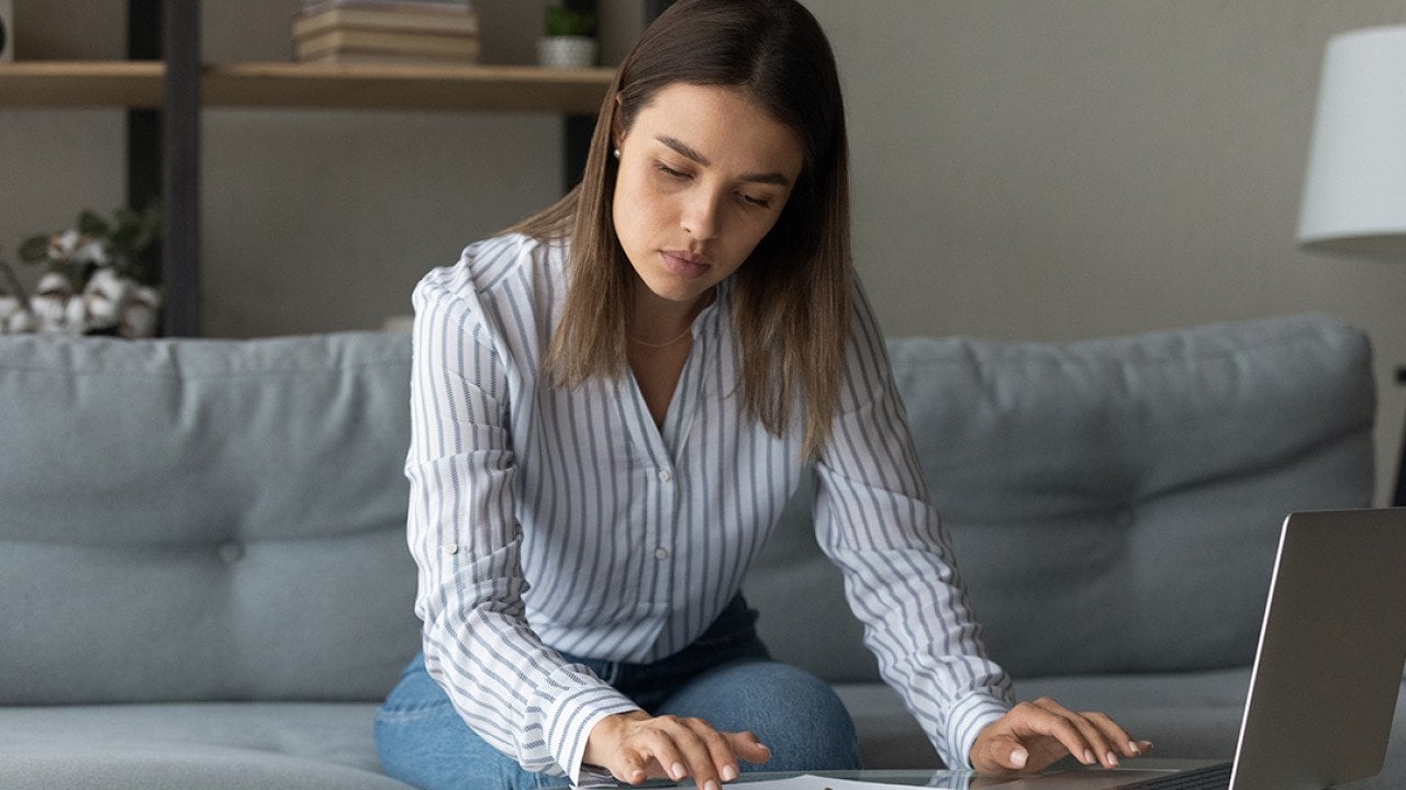 A focused woman at home reviewing financial reports.