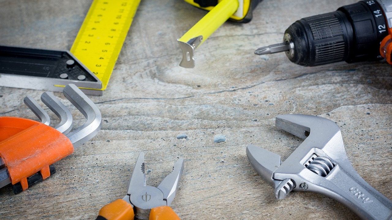 Assorted construction hand tools scattered on a work surface.