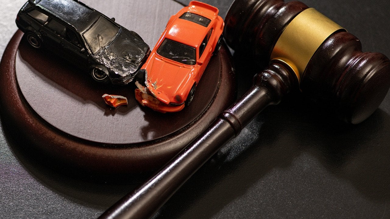 Figures of crashed cars and a gavel as a concept of traffic court civil litigation.